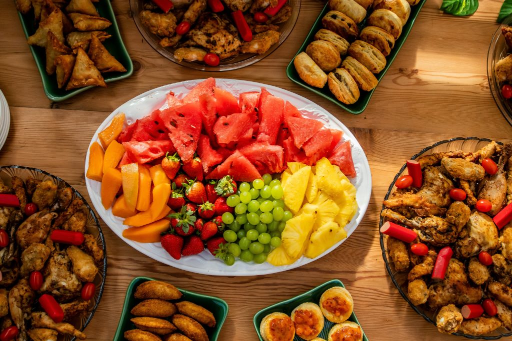 A colourful kids birthday party food table with sandwiches, fruit skewers and party snacks